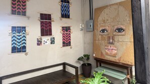 Quarto com parede decorada por tapeçarias estampadas e um grande quadro abstrato.