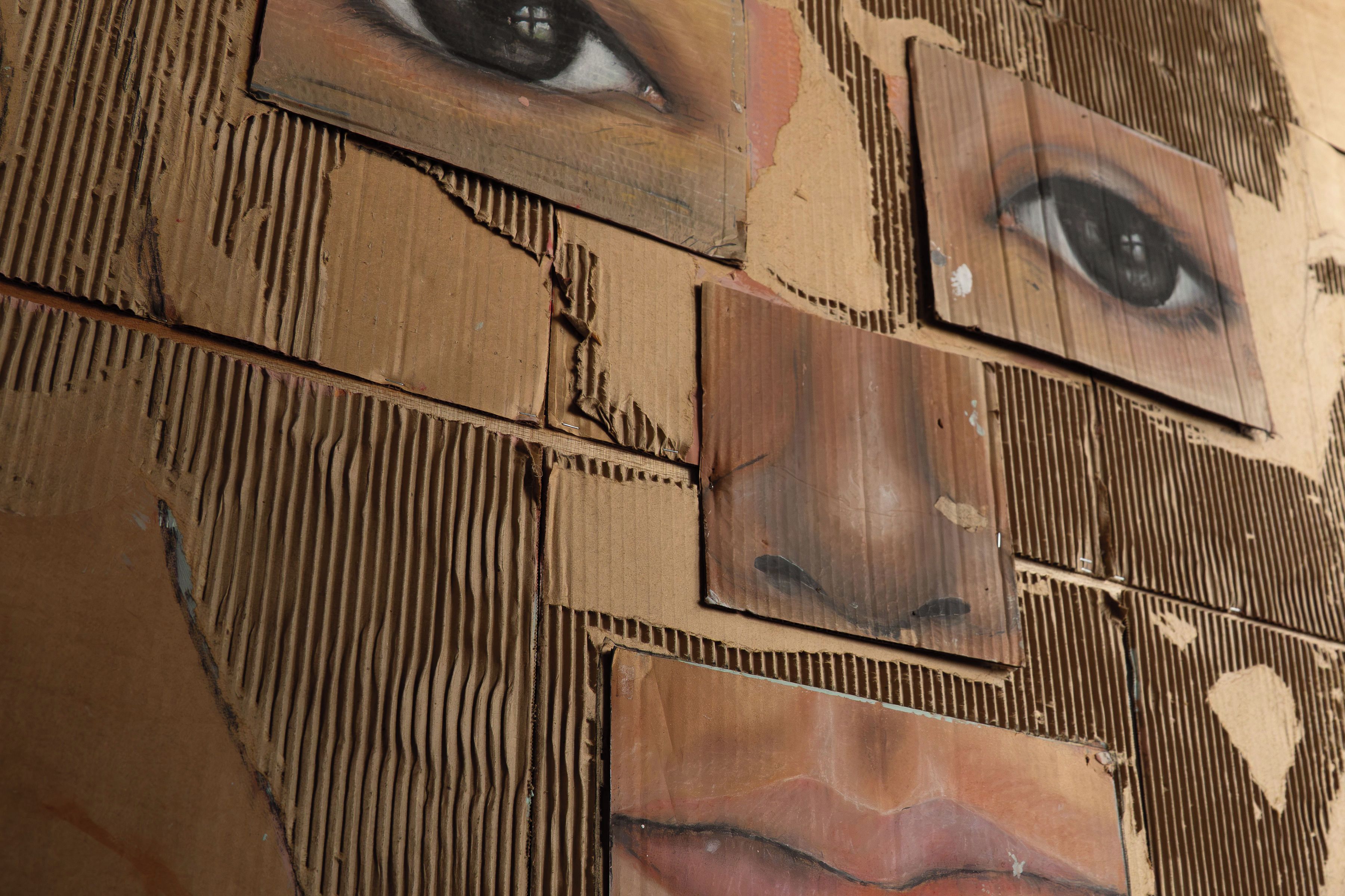 Una pared con varias obras de arte, incluyendo retratos de ojos y rostros.