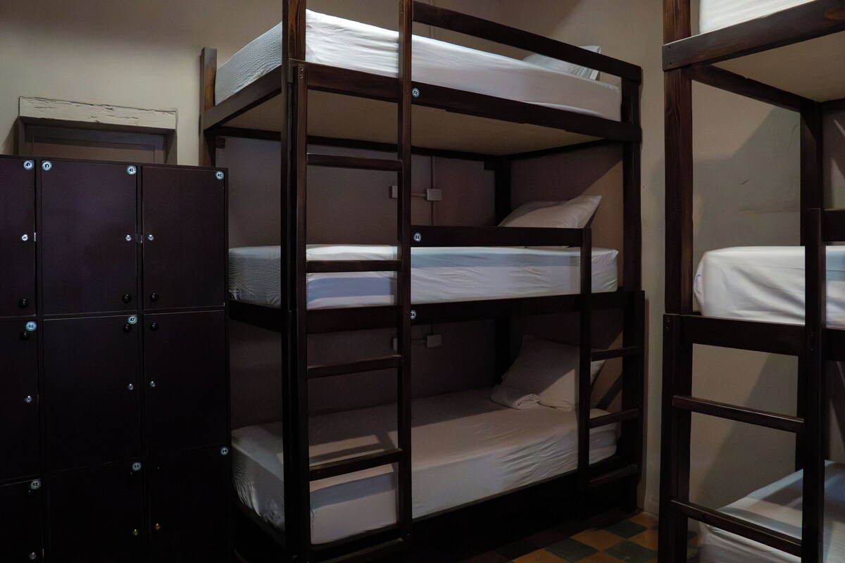 Bunk beds with storage lockers, a tiled floor, and a plain wall.
