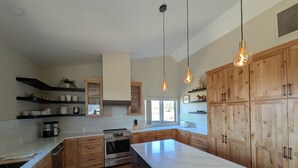 Uma cozinha moderna com armários de madeira, uma ilha grande e iluminação pendente.