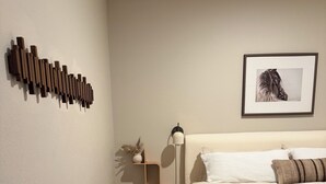 Quarto com cama, mesa de cabeceira, abajur, tapete e luminária na parede.