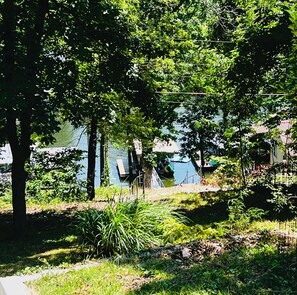 A lush garden with trees, a small water feature, and a wooden deck.