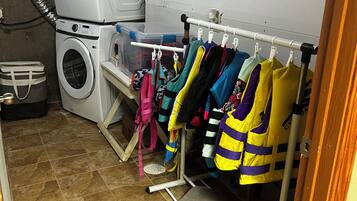 Un espace buanderie comprenant un lave-linge, un étendoir et des bacs de rangement.