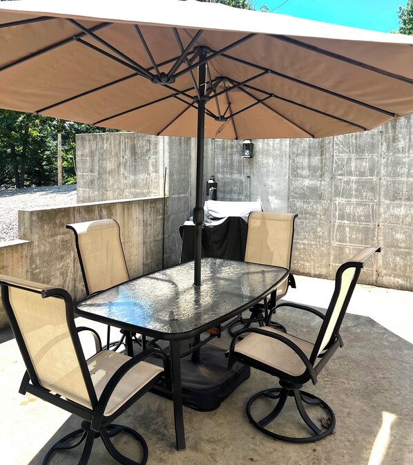 An outdoor patio with a round table, four chairs, and a large umbrella.