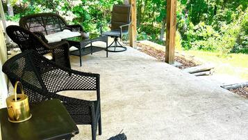 Un patio couvert aménagé avec des meubles en osier, une table et une chaise.