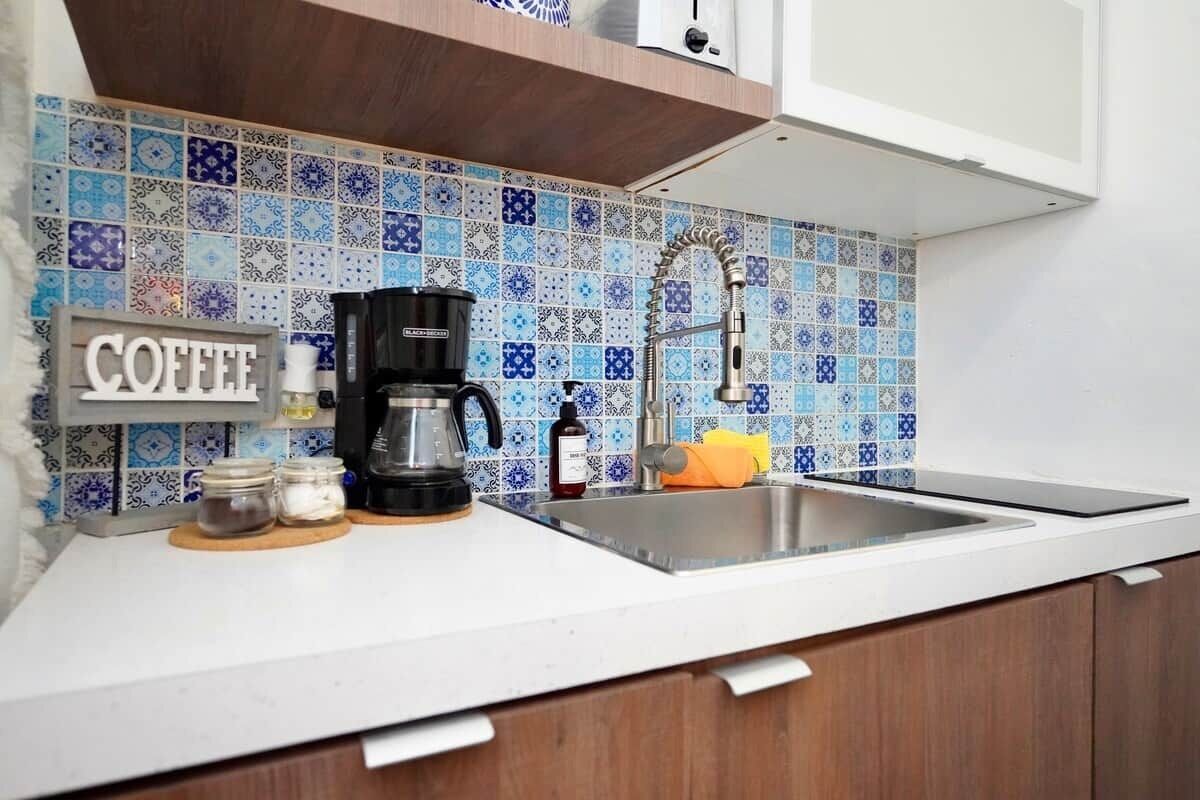 Una cocina con cafetera, frascos y pileta.