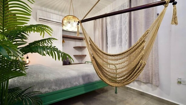 A room with a green bed, a hammock, and a hanging light fixture.