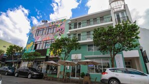 A building with a colorful mural, outdoor seating, and a white car parked in front.
