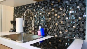 A kitchen with a black hexagonal backsplash, stainless steel sink, and modern faucet.