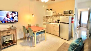 A compact kitchen with a microwave, refrigerator, and a dining area with chairs and a table. - 1.7 • Balcony • Generator • Parking • 2nd Floor (Mayagüez)