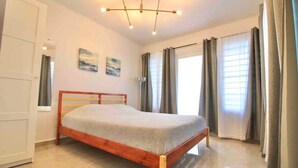 A bedroom with a wooden bed, a white door, and a ceiling light fixture. - 1.7 • Balcony • Generator • Parking • 2nd Floor (Mayagüez)