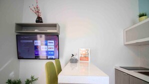 A reception desk with a mounted TV displaying streaming services, a manual guidebook, and a potted plant.
