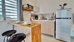 A modern kitchen with a microwave, refrigerator, and wooden bar counter.