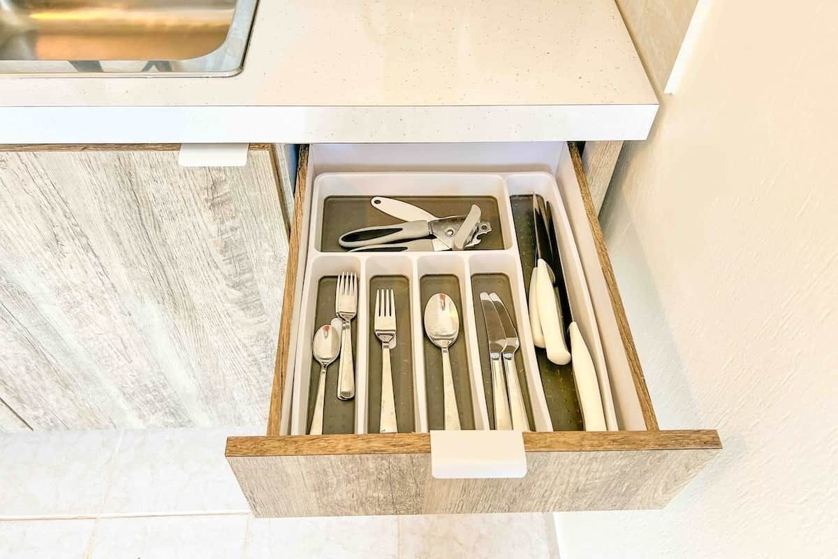 Un cajón con cubiertos ordenados, incluyendo tenedores, cucharas y cuchillos.