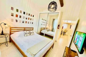 Una camera da letto con un letto, una lampada da comodino, opere d'arte a parete, uno specchio e una TV.