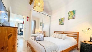 Une chambre à coucher avec un lit en bois, une table de chevet, un miroir et des œuvres d’art accrochées au mur.