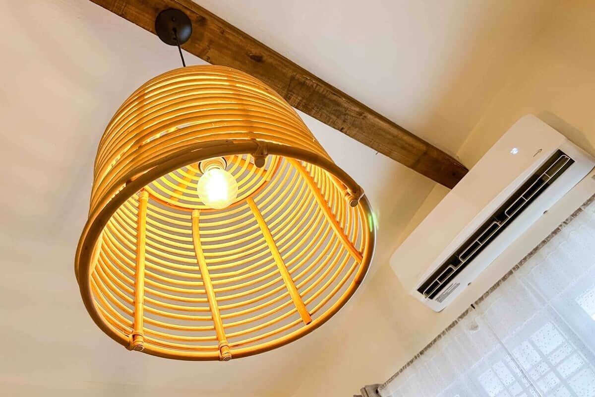 A hanging light fixture with a circular design and a ceiling-mounted air conditioning unit.