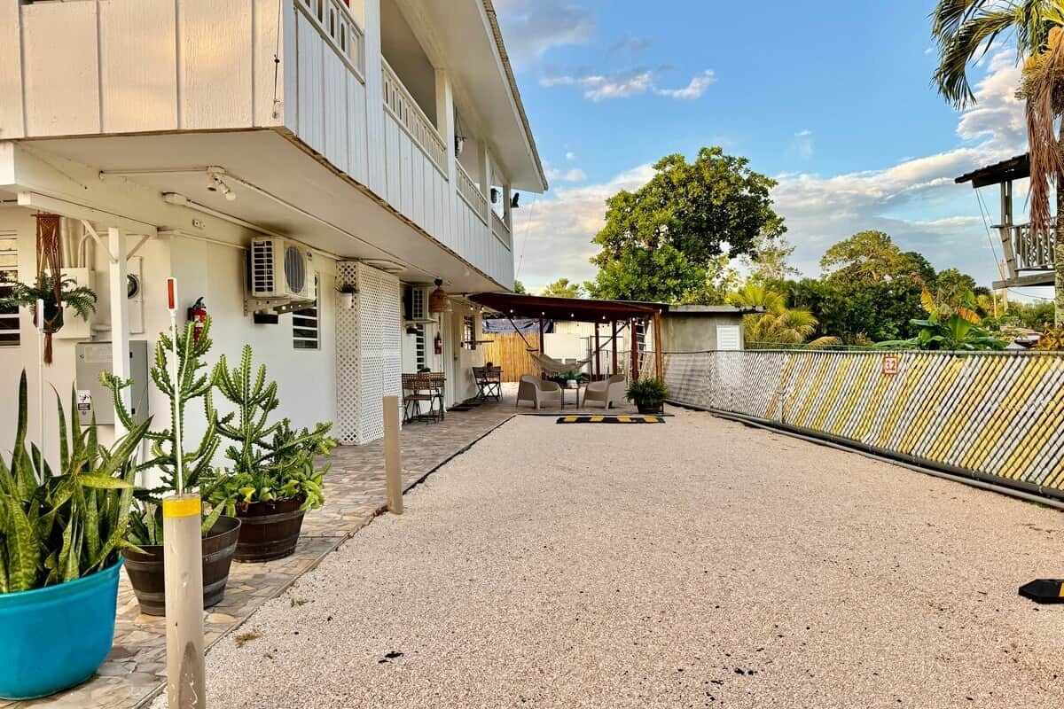 Un edificio de dos pisos con un patio cubierto, mobiliario exterior y plantas en macetas.