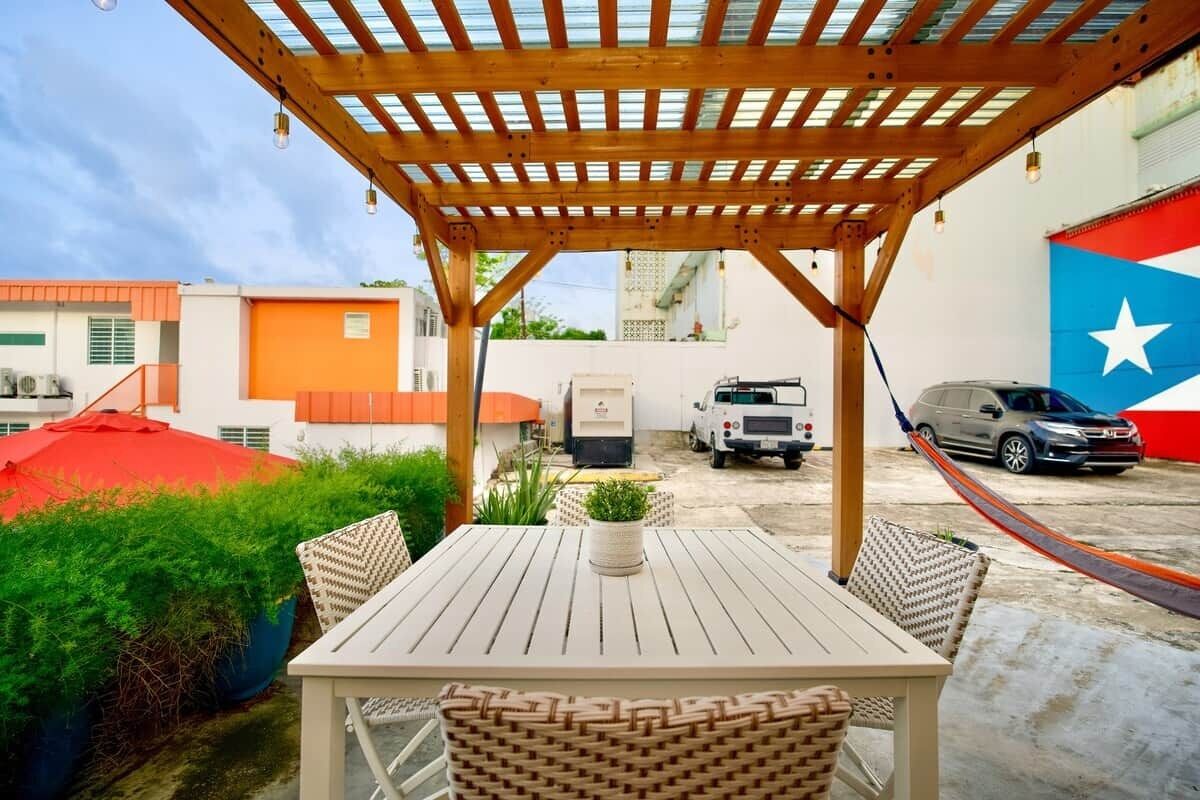 An outdoor patio with a wooden pergola, a table, and chairs.