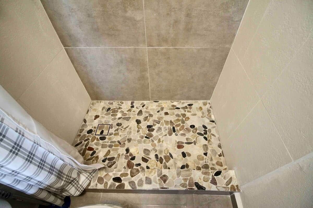 A corner of a bathroom with a mosaic tile floor, a shower area, and a towel rack.