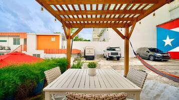 Un patio al aire libre con una pérgola de madera, una mesa y sillas.