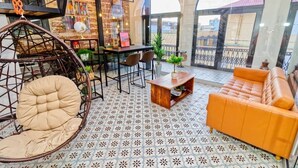 A cozy interior with a hanging chair, a sofa, a dining table, and a view through large windows. - 5.2 Loft • Lobby • Generator • Parking • 2nd Floor (Mayagüez)