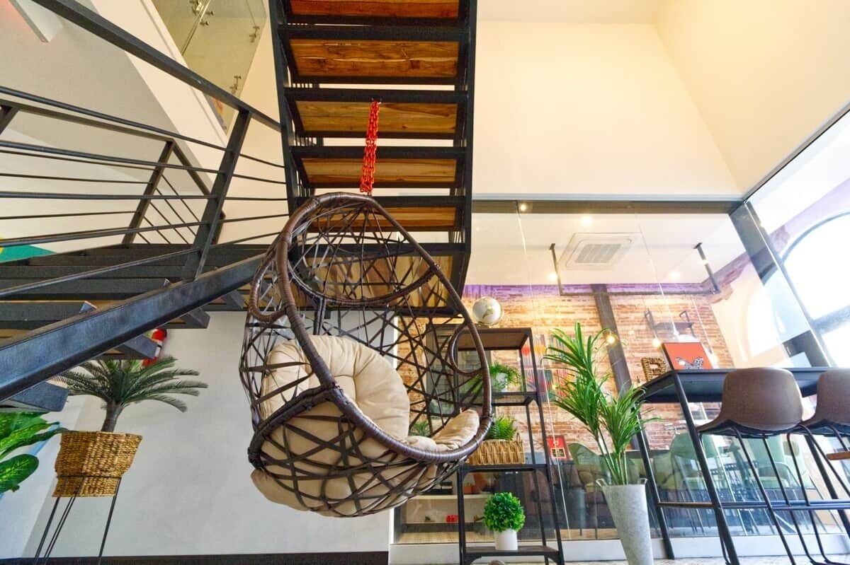 Een modern interieur met een spiltrap, hangstoelen van wilg, en kamerplanten.
