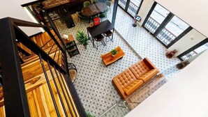 A modern interior with a staircase, a round dining table with chairs, a sofa, and a patterned floor. - 5.2 Loft • Lobby • Generator • Parking • 2nd Floor (Mayagüez)