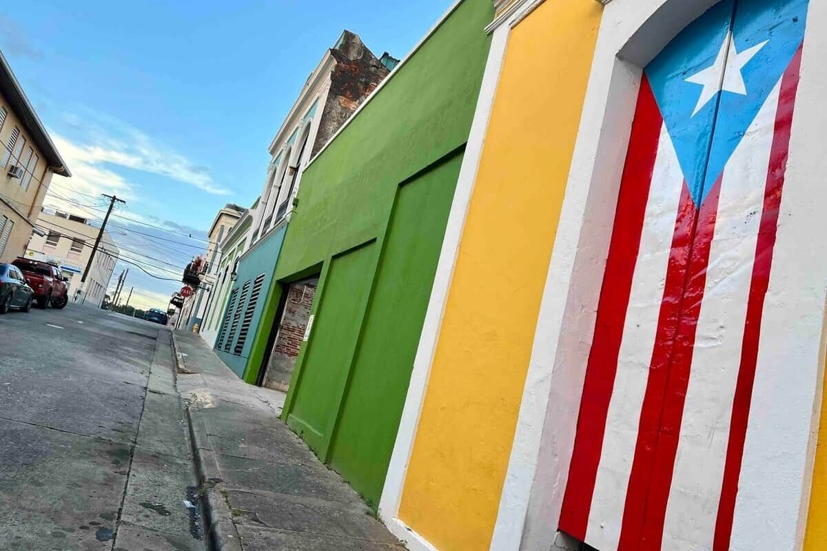 Una calle con edificios pintados de verde, amarillo y rojo.