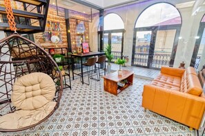 Un ambiente acogedor con una silla colgante, un sofá, una mesa de comedor y vistas a través de grandes ventanales.