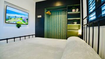 A bedroom with a bed, a television mounted on the wall, and a wardrobe with a herringbone pattern.