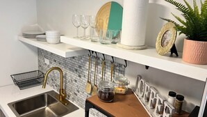 A kitchen with a sink, a wooden countertop, and a shelf with glassware and a plant. - 3.9 Near Beach • Generator • Hammock • 1st Floor (Miradero)