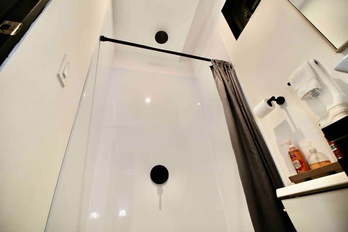 Un baño moderno con cabina de ducha de vidrio, un perchero y una cafetera sobre la encimera.