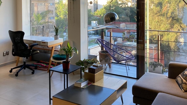 A modern living room with a large window, a sofa, a desk, and a chair. - Very Private Shared Room with Private Bathroom and Terrace (Ciudad de México)