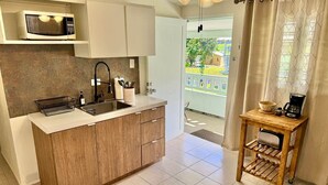 A kitchen with a microwave, sink, and wooden cabinets. - 3.5 Near Beach • Generator • Hammock • 2nd floor (Miradero)