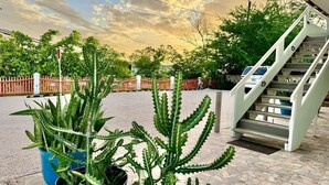 A staircase leading to a building, a potted plant, and a fenced area with trees. - 3.5 Near Beach • Generator • Hammock • 2nd floor (Miradero)