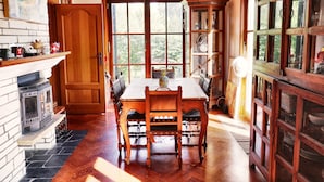 A dining area with a wooden table, chairs, a fireplace, and a large window.