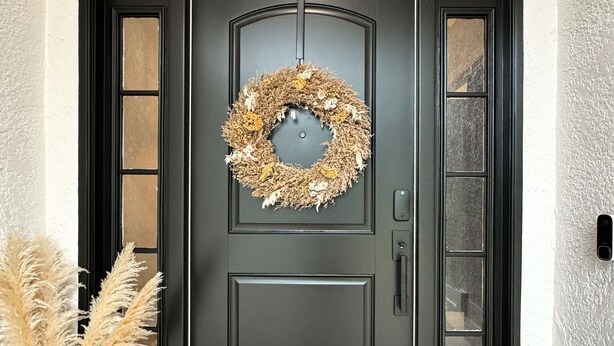 A black front door with a wreath, a doormat with 'hello,' and a woven basket. - Beautiful 4-bedroom house with AC in Wimauma (Wimauma)