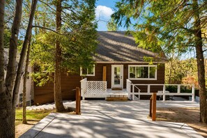 A wooden cabin with a porch, surrounded by trees. - Lake Arrowhead Mountain Hideaway by Navigate Stays (Lake Arrowhead)