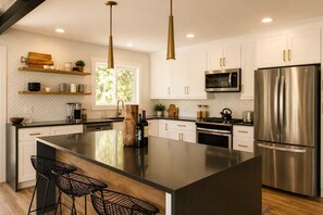 A modern kitchen with a large island, stainless steel appliances, and pendant lighting. - Lake Arrowhead Mountain Hideaway by Navigate Stays (Lake Arrowhead)