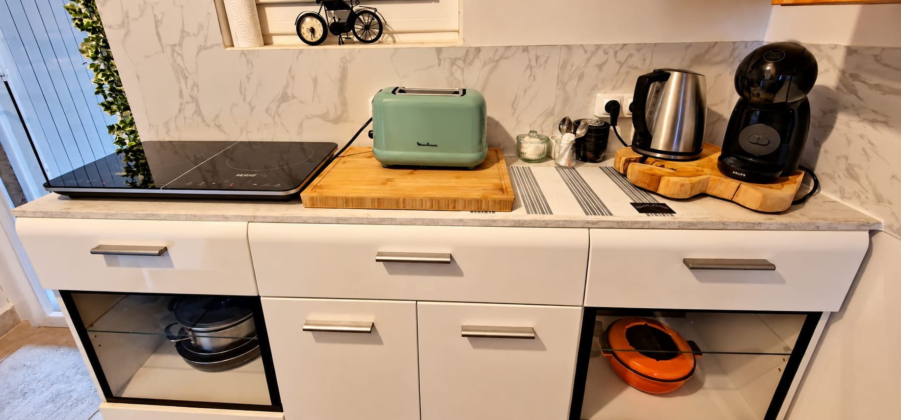Eine Küche mit Laptop, Toaster, Kaffeemaschine und einem kleinen Fahrrad auf der Arbeitsfläche.