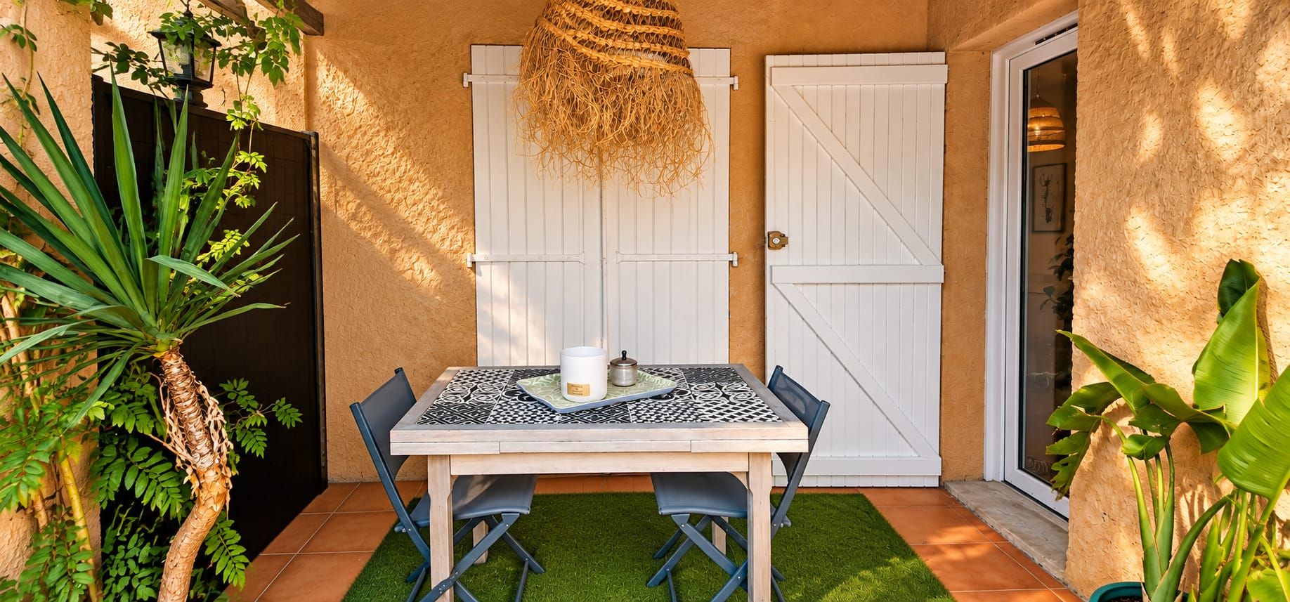 Un espace patio avec une table et des chaises, un luminaire suspendu et une porte.