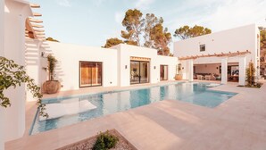 A modern pool area with a clear sky, a pool, and a building with large windows and a covered patio. - Fully Staffed Seafront Villa Private Sommelier (Teulada)