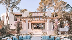 A modern outdoor living area with a circular seating arrangement, a pergola, and a pool. - Fully Staffed Seafront Villa Private Sommelier (Teulada)
