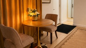 Une pièce comprenant une table ronde en bois, deux chaises, un vase avec des fleurs, une lampe et un grand miroir.