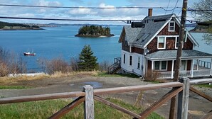Um deck de madeira com vista para uma casa e um lago.