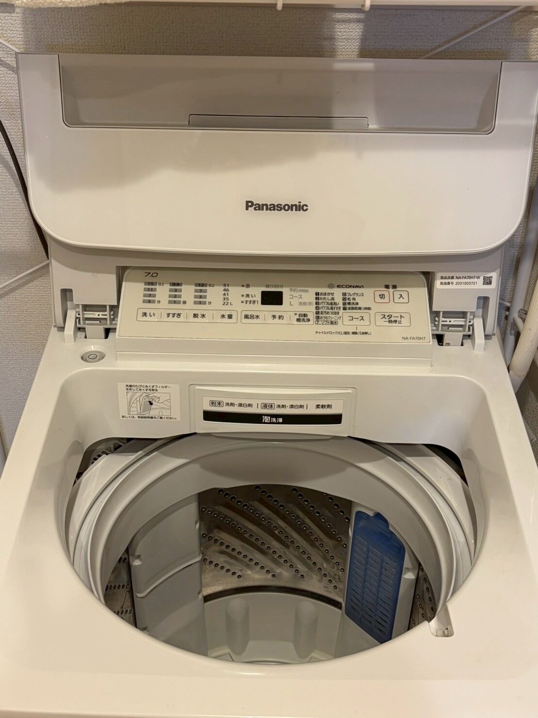 A Panasonic washing machine with a control panel, a transparent door, and a blue instruction card inside.