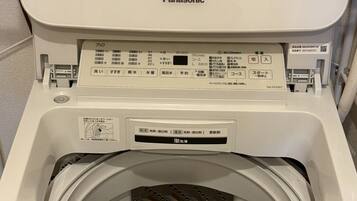 A Panasonic washing machine with a control panel, a transparent door, and a blue instruction card inside.
