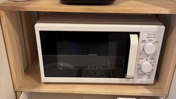 A microwave and a rice cooker on a shelf, with a drawer below containing kitchen utensils.