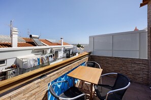 A rooftop terrace with a table and chairs, a view of the city, and a white wall. - Tiny Home 'Escadaria' with Sea View, Balcony and Wi-Fi (Lagos)